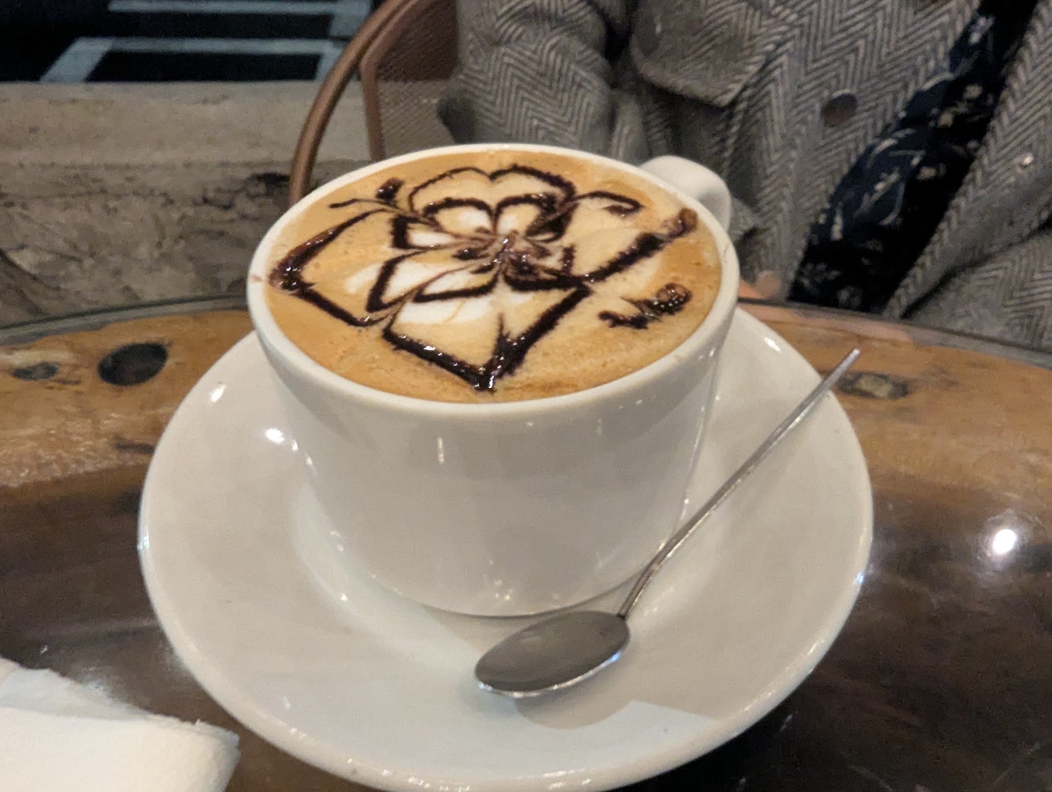 Coffee with chocolate latte art in a white cup and saucer.