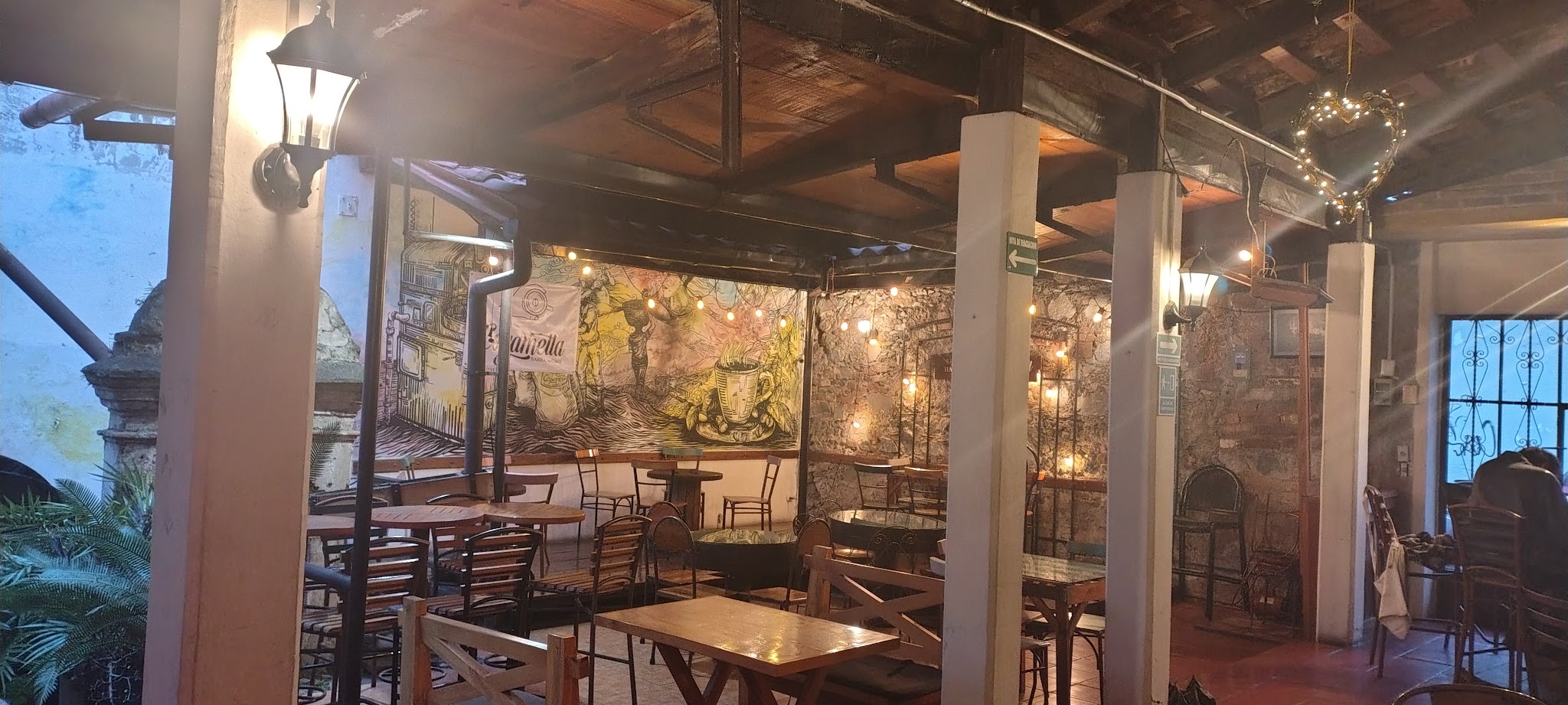 Warmly lit café interior with tables, chairs, and wall art.